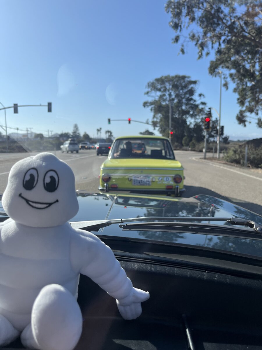 A dashboard mascot joins the drive with a bright BMW following behind