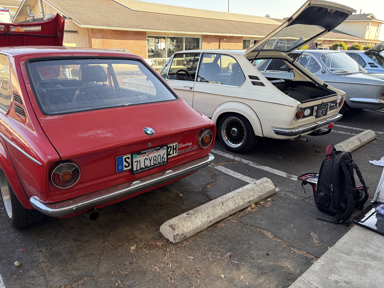 Red and white BMW Touring models parked together, with a hatch open
