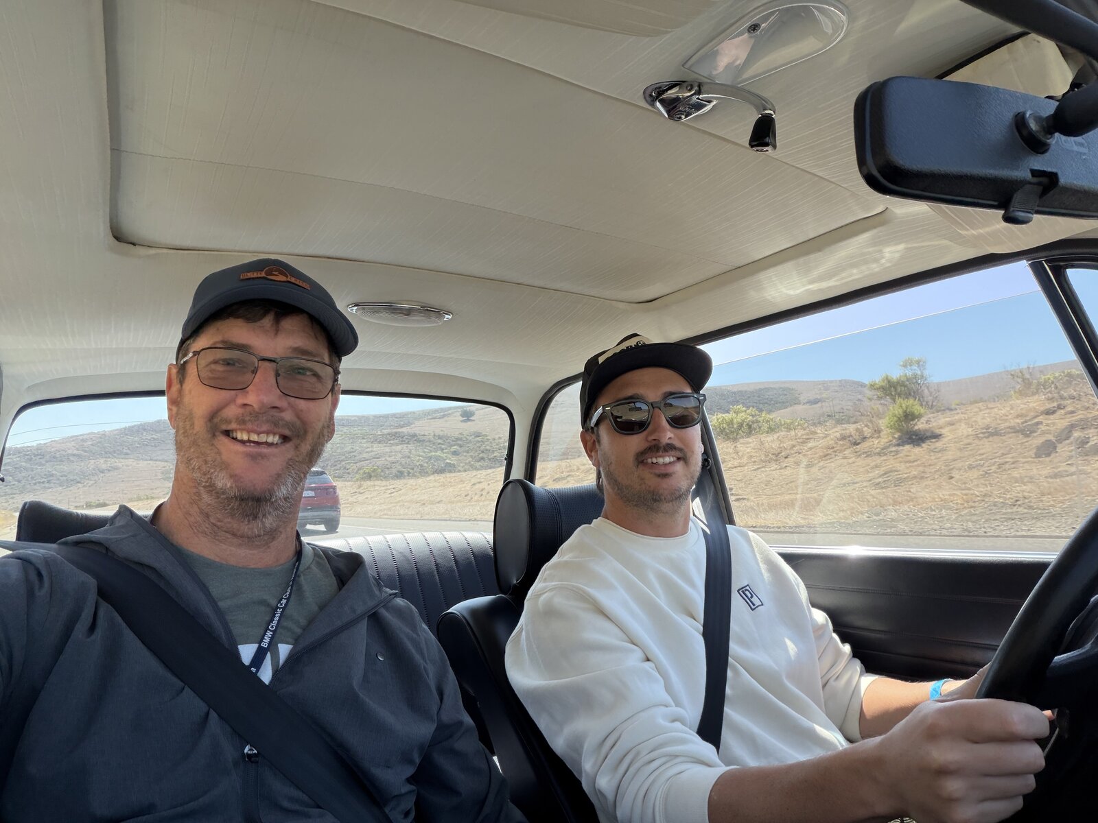 Two smiling enthusiasts enjoying the drive together