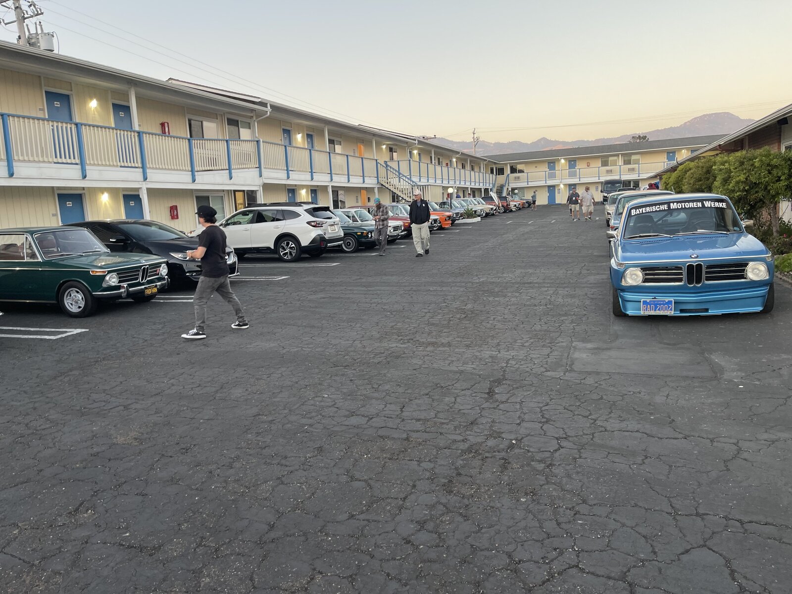 Enthusiasts walking among classic BMWs in the Coast Riders Inn courtyard